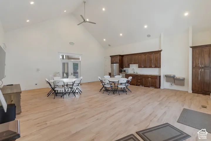 Vaulted ceiling with recessed lighting, wood-finish flooring, full kitchen with wood cabinetry and stainless steel appliances, and French doors to the exterior