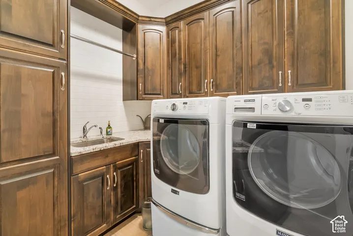 Rich wood-finish cabinetry, white subway tile backsplash, integrated sink with chrome faucet, light-toned countertop, and a clothes hanging rod