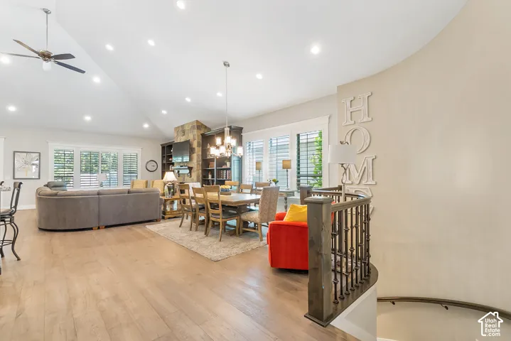 entrance leading into great room with vaulted ceilings with recessed lighting, wood-finish flooring, stone-clad fireplace with built-in shelving, chandelier, and a curved staircase with wrought iron balusters