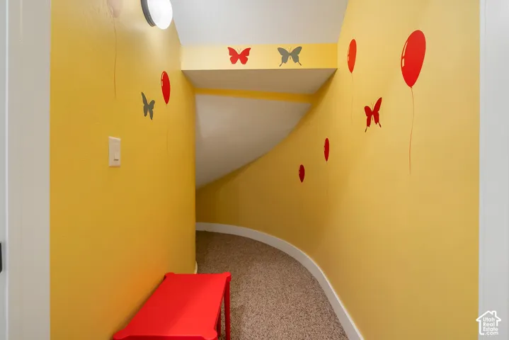 Curved hallway with wall-mounted lighting and carpeted flooring