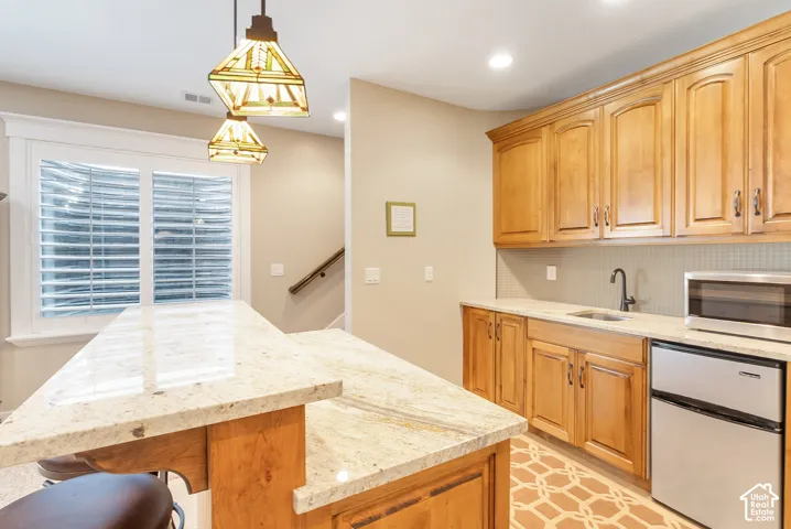 Kitchenette with wood cabinetry, light-toned countertops, and a built-in sink