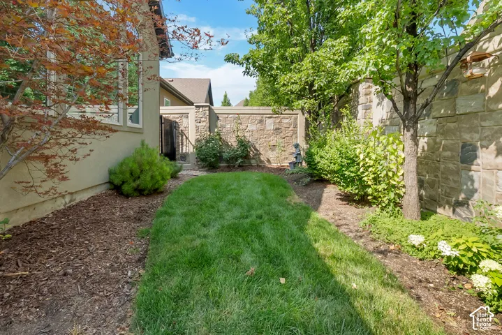 Manicured lawn area with stone retaining walls, mature trees, and established plantings