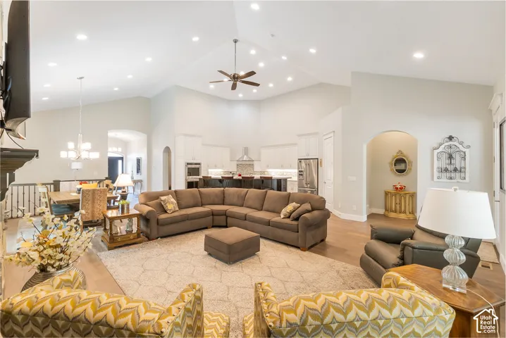 Vaulted ceilings with recessed lighting, an open-concept layout, wood-finish flooring, a kitchen featuring stainless steel appliances, and a built-in kitchen island with seating