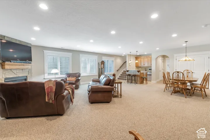 Spacious living area featuring a stone-clad fireplace, recessed lighting, and large windows with plantation shutters