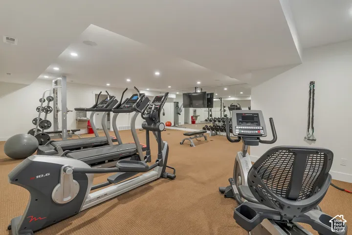 Dedicated fitness area featuring recessed lighting, a full-wall mirror, and carpeted flooring