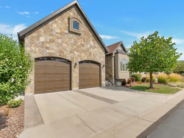 Stone veneer exterior with arched garage doors, an arched window, and a concrete driveway