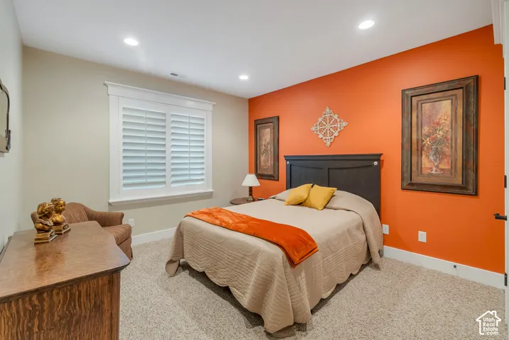Recessed lighting, white plantation shutters, dark wood-finish headboard, and carpeted flooring