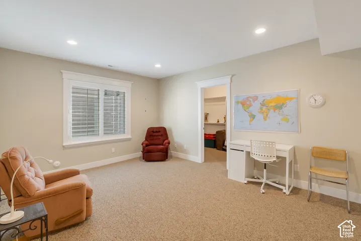 Spacious room with neutral-toned walls, recessed lighting, a window with horizontal blinds, and a doorway leading to an additional space