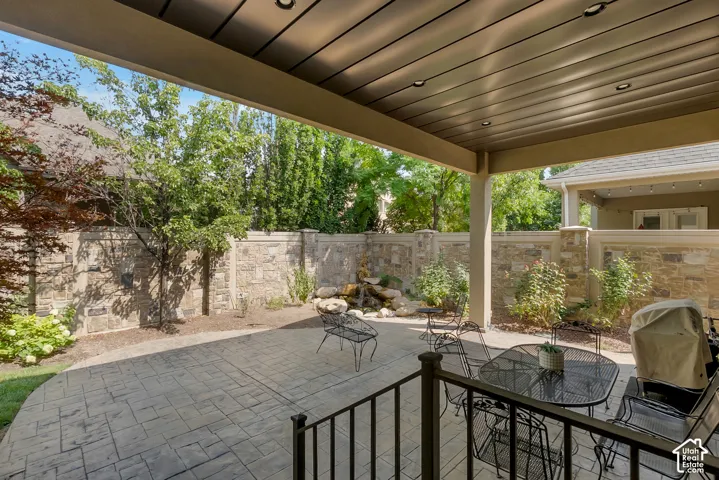 Covered patio with recessed lighting, stamped concrete flooring, stone privacy wall, and a built-in rock water feature