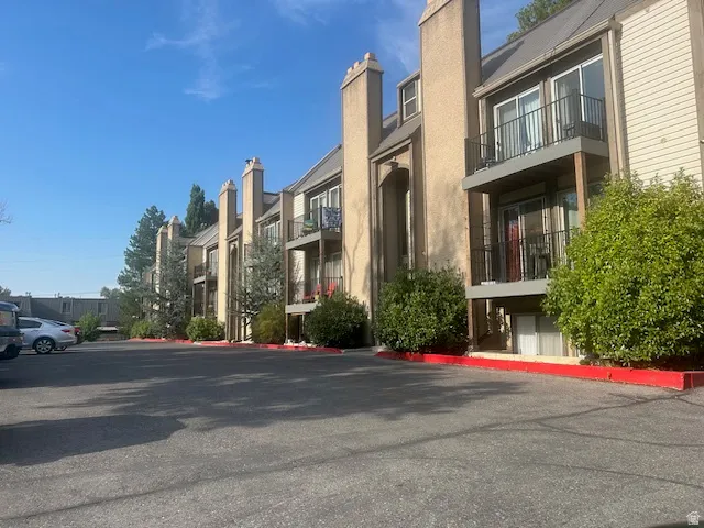 Multi-story building featuring balconies with black railings, stucco and siding exterior, and prominent chimneys