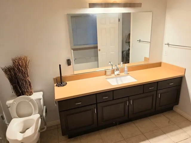 Extended vanity with a built-in sink, dark wood-finish cabinetry, and a full-width mirror