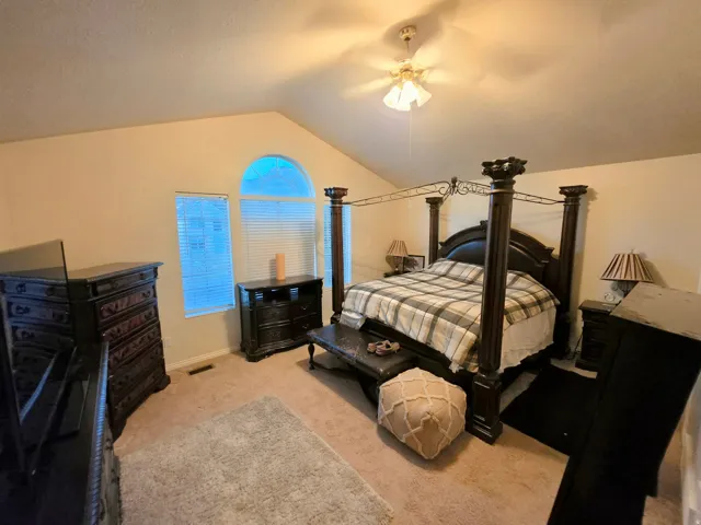 Vaulted ceiling with a ceiling fan, arched window, and two rectangular windows