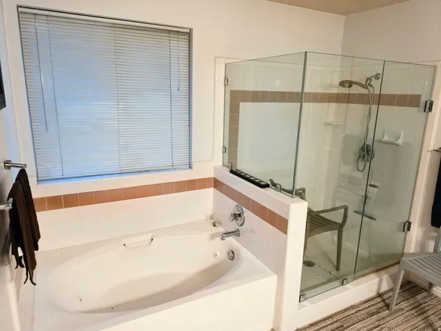 Built-in soaking tub, separate glass-enclosed shower, and tiled surround
