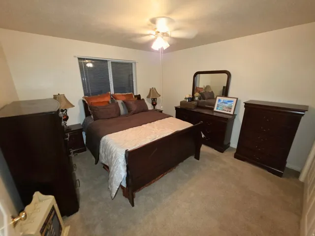 Carpeted flooring, ceiling fan with integrated lighting, and a window with blinds