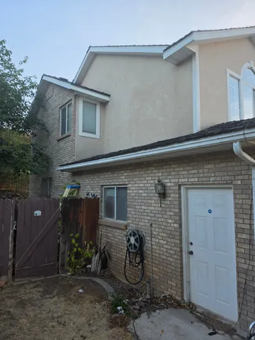 Exterior featuring brick and stucco finishes, white-framed windows, and a side entry door