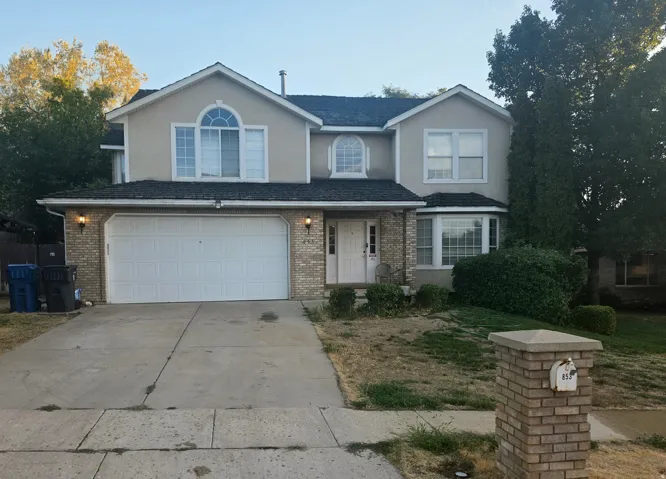 Two-story stucco and brick exterior featuring a multi-pane arched window, an integrated two-car garage, and a bay window