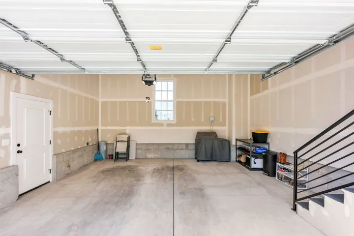 Spacious garage with concrete flooring, a single window, and a white access door