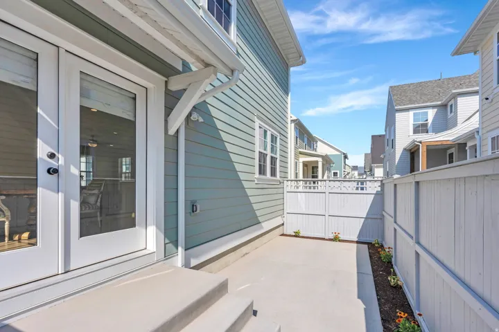 French doors with clear glass panes and black hardware, leading to a concrete patio