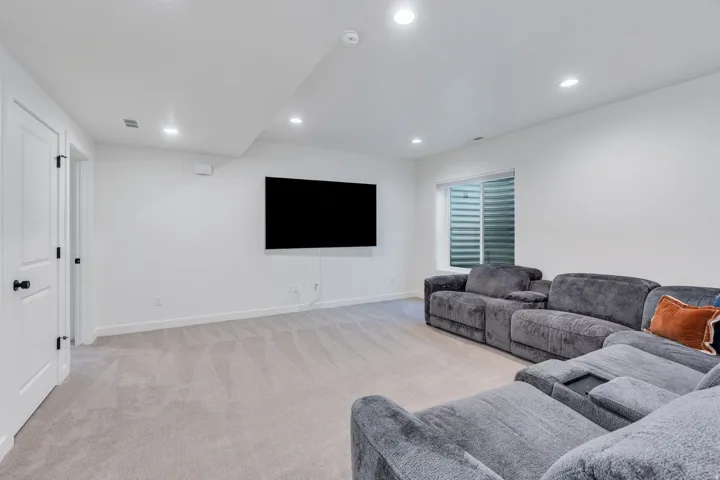 Recessed lighting, light-colored carpeting, white interior doors with black hardware, and a window with blinds