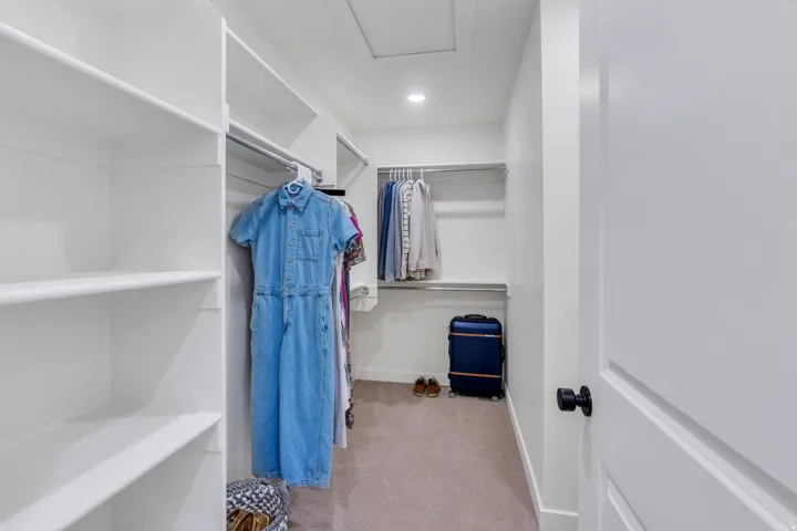 White built-in shelving, chrome hanging rods, recessed ceiling lighting, and carpeted flooring