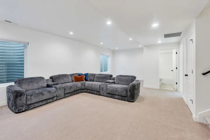 Recessed lighting, light-colored carpeting, white wall finishes, and a secondary space