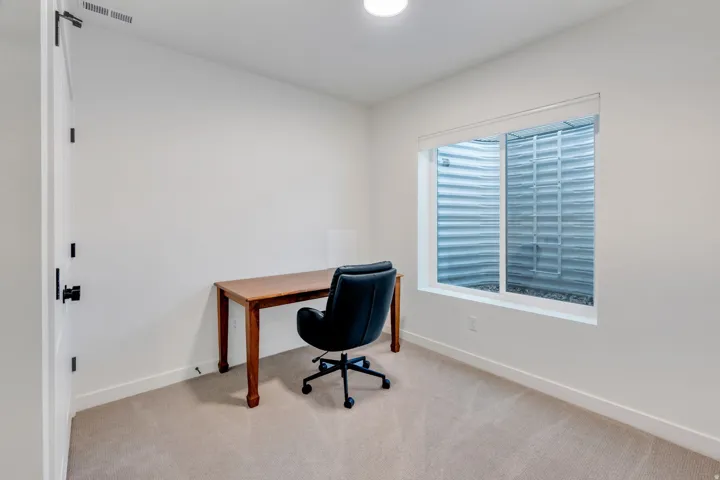 Neutral wall paint, carpeted flooring, white trim, and a white interior door with matte black hardware
