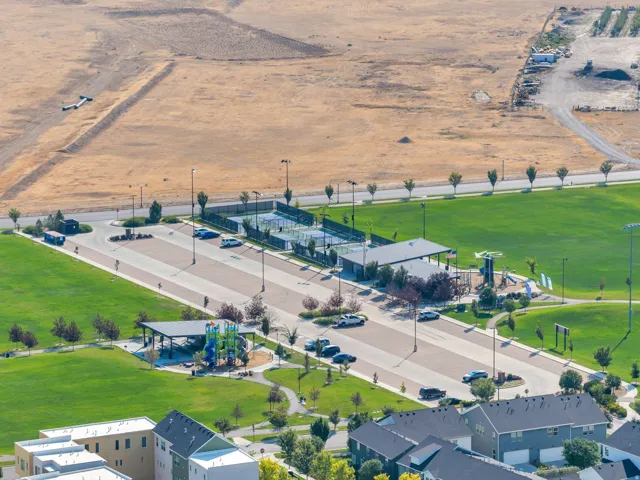 Community amenities featuring multiple tennis courts, a children's play area, covered picnic structures, and expansive green spaces