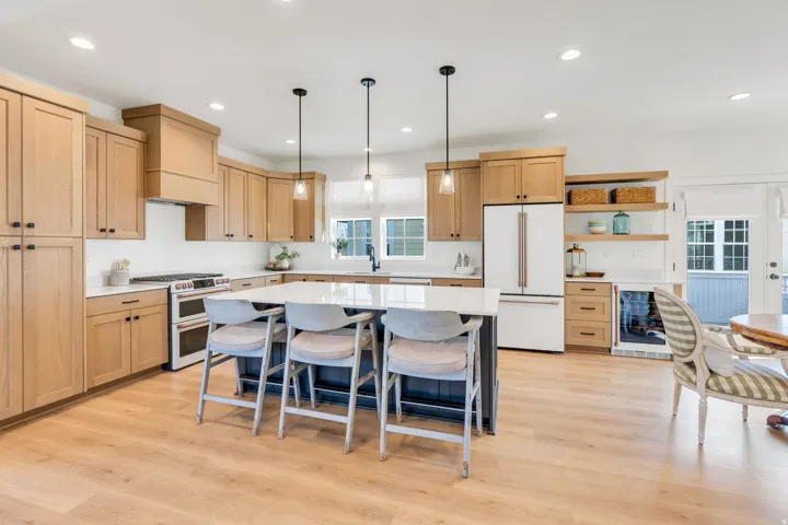 Kitchen featuring light wood-finish cabinetry, white countertops, a central island with pendant lighting, a stainless steel range, and wood-finish flooring