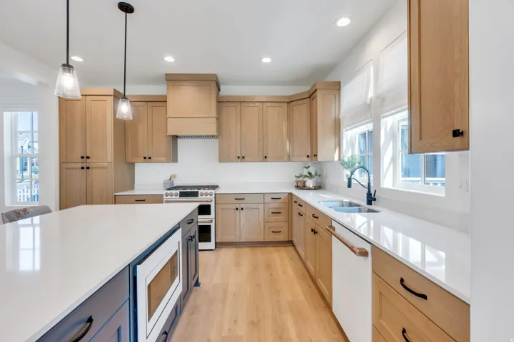 Kitchen featuring light wood-finish cabinetry, a large center island with a built-in microwave, white countertops, and wood-finish flooring