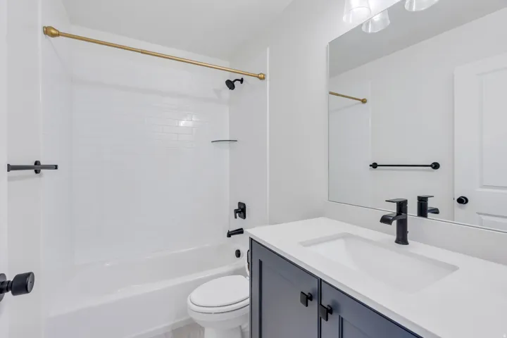 White subway tile shower surround with a gold-tone shower rod