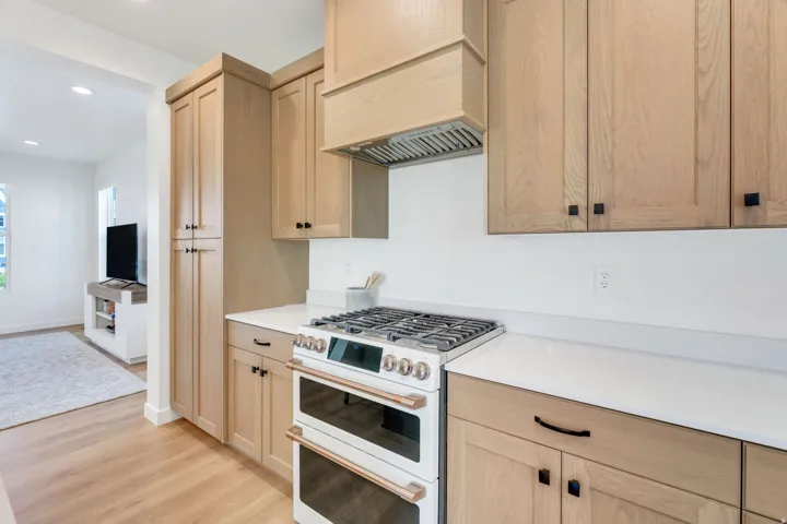 White countertops with wood-finish cabinetry and black hardware