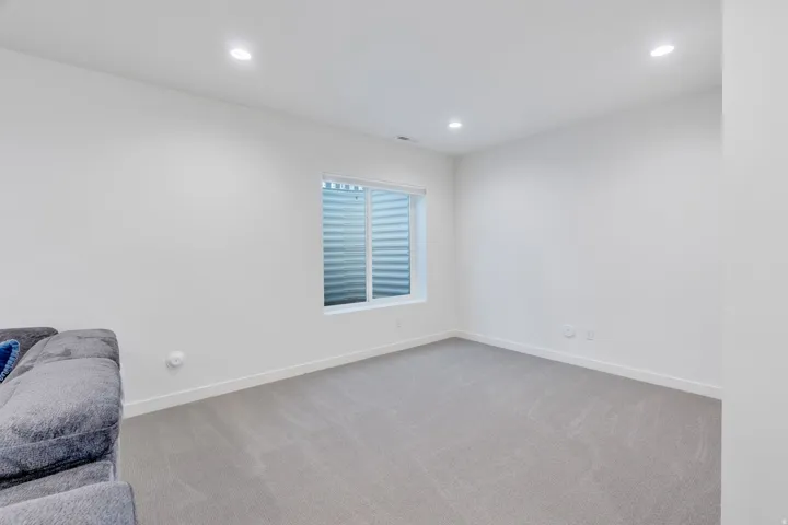 Recessed lighting, light gray carpeting, and a white window frame with blinds