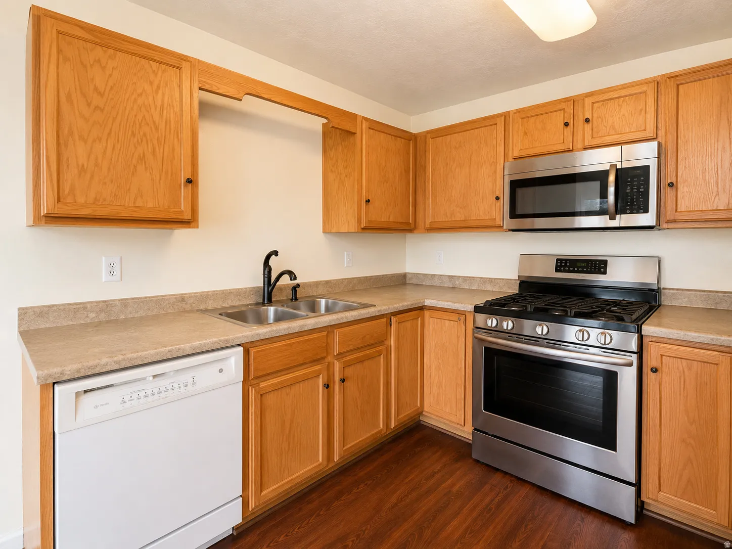 Kitchen featuring wood-finish cabinetry, stainless steel microwave, and gas range