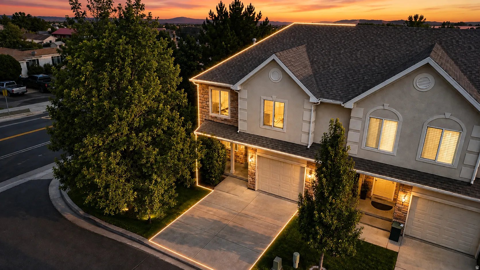 Stucco and stone facade, arched window detailing, attached garages, paved driveway, mature trees