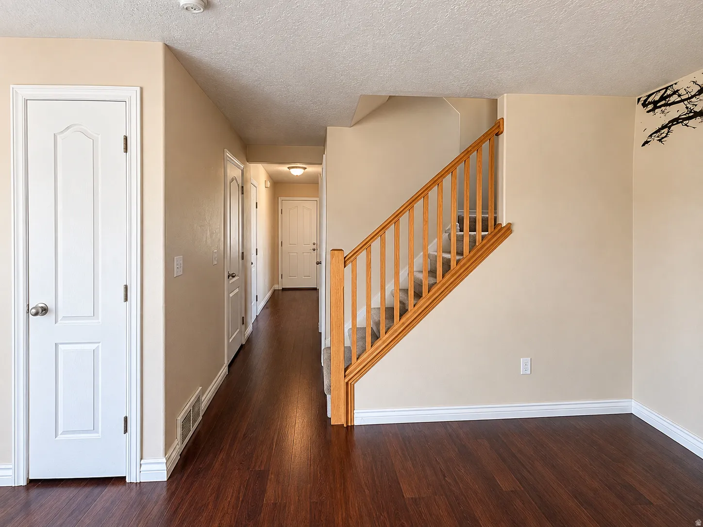 Hardwood-finish flooring throughout, stairway with wood railing and carpeted treads, and neutral wall tones