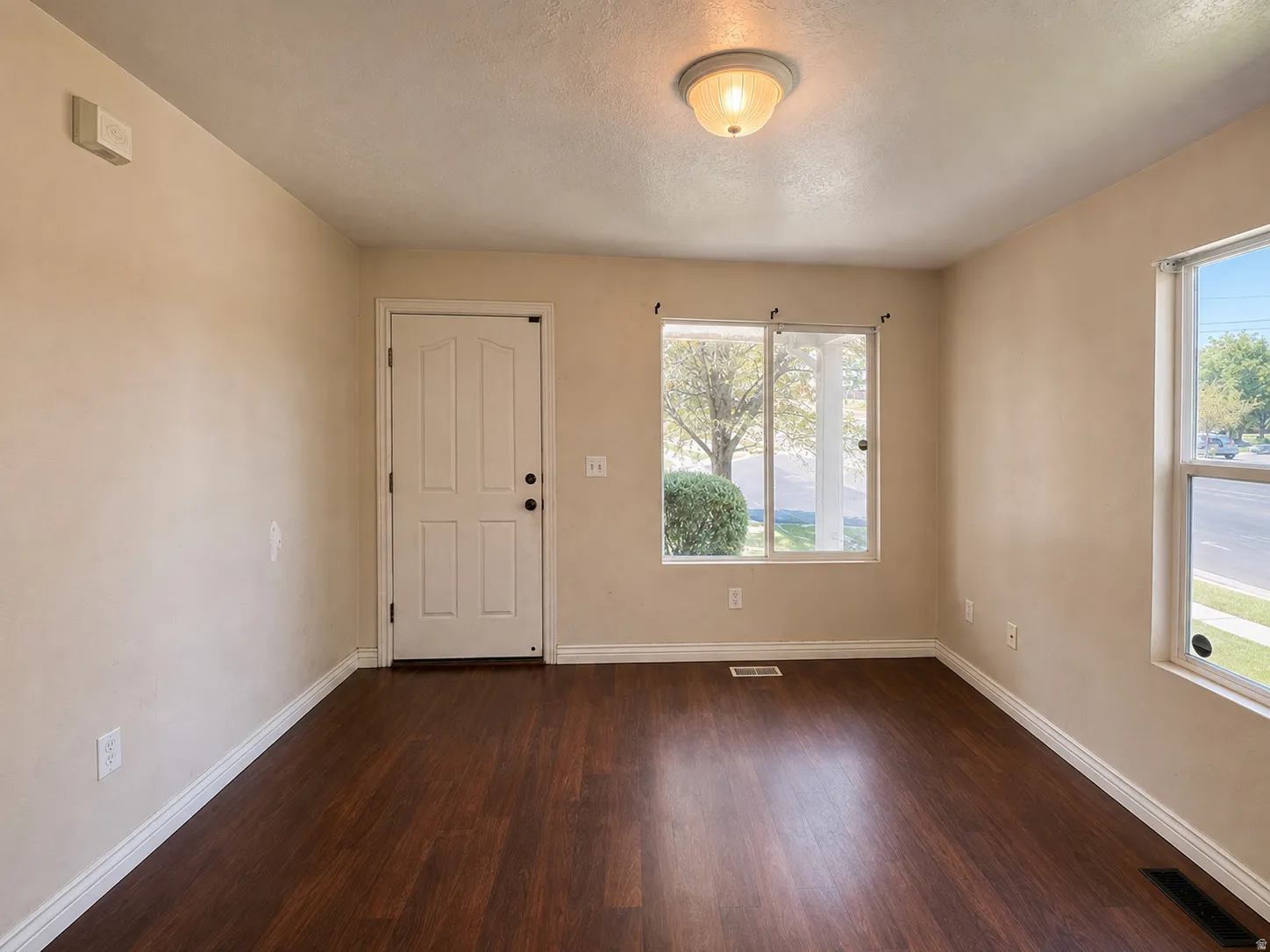 Wood-finish flooring, neutral wall paint, white trim, and a ceiling-mounted light fixture