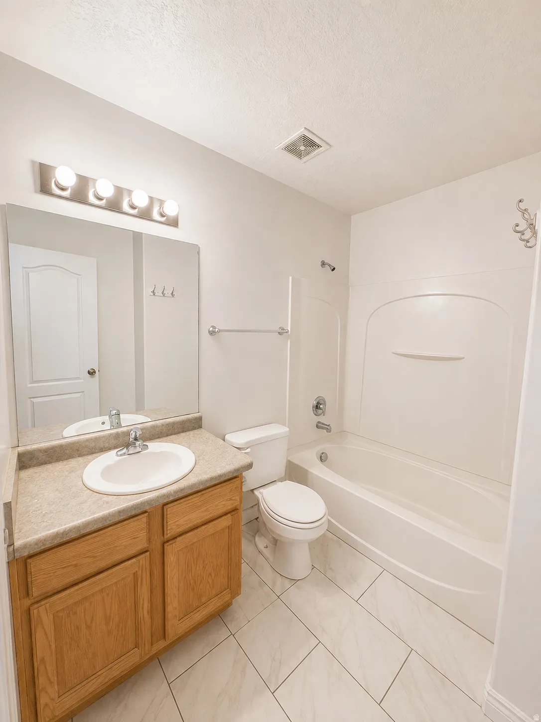 Bathroom with a wood-finish vanity, integrated sink, and a combination tub/shower