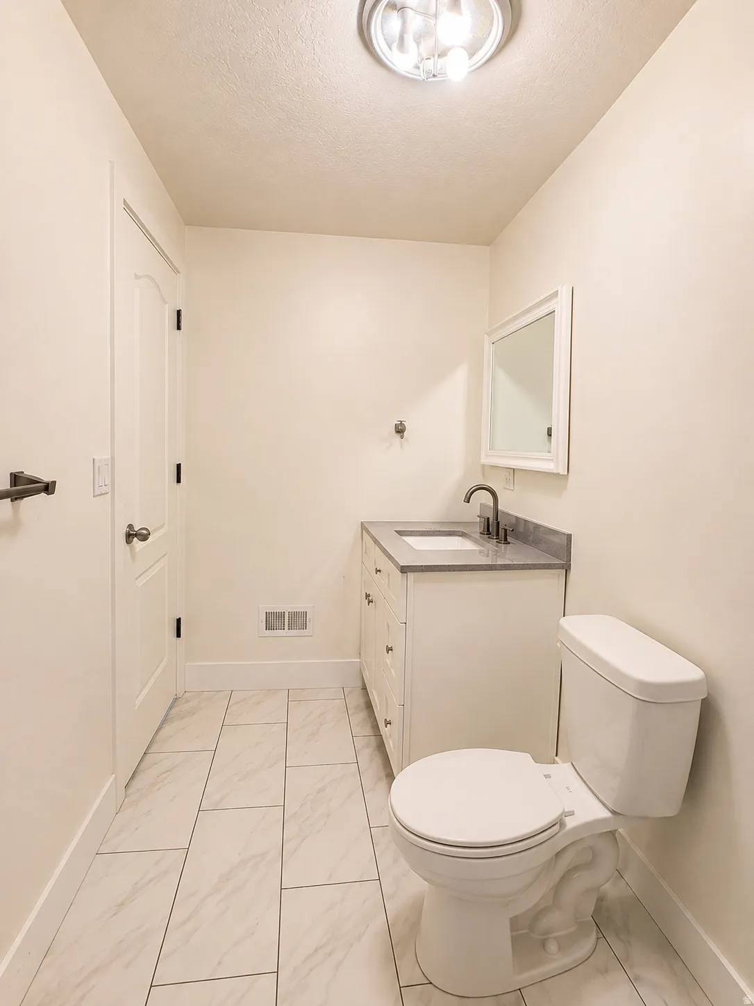 White vanity with a single sink, framed mirror, and dark-toned faucet