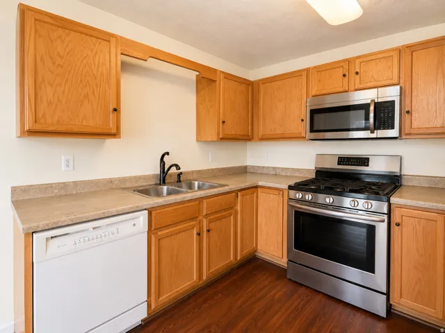 Kitchen featuring wood-finish cabinetry, stainless steel microwave, and gas range