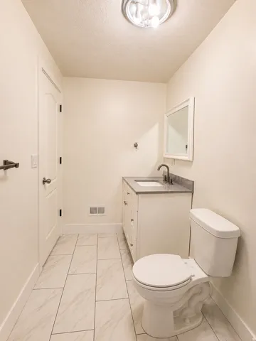 White vanity with a single sink, framed mirror, and dark-toned faucet