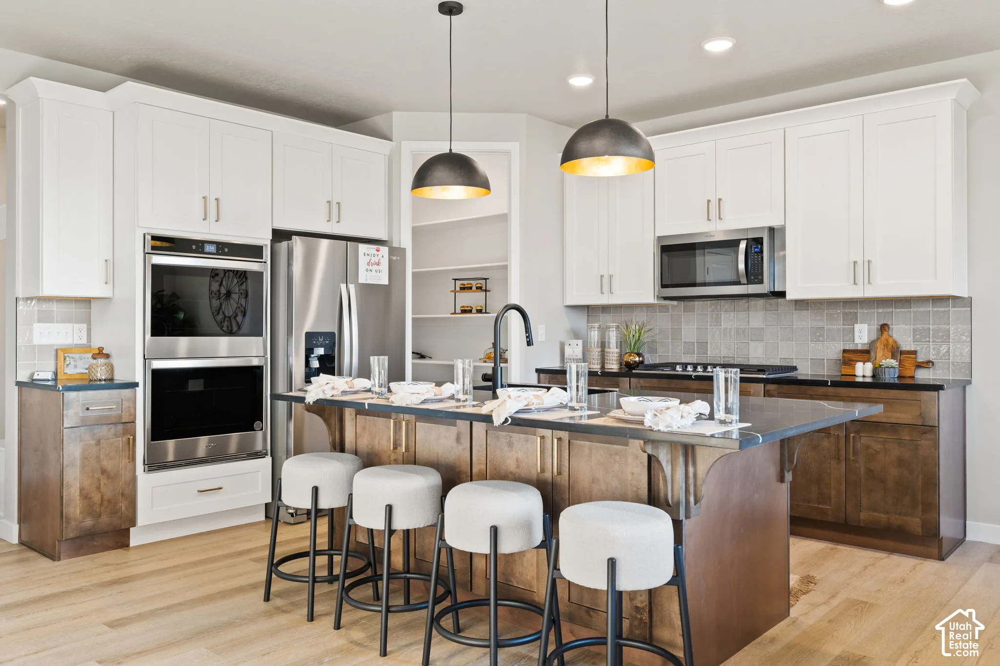 Kitchen featuring two-tone cabinetry, stainless steel appliances, a center island with seating, a tile backsplash, and recessed lighting
