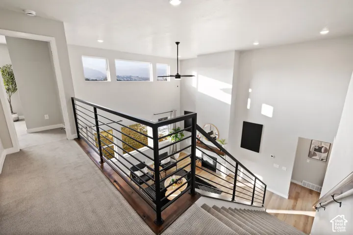High ceilings with recessed lighting, carpeted stairs, and a black metal railing system