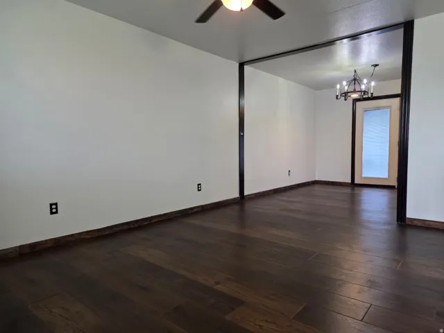 Spacious open-concept living area showcasing dark wood-finish flooring, neutral walls, and abundant natural light