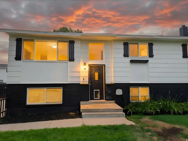 Split-level residence featuring white siding and a black lower exterior