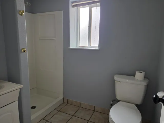 Functional bathroom featuring ceramic tile flooring, a toilet with tank, pedestal sink, and a walk-in shower enclosure with glass door