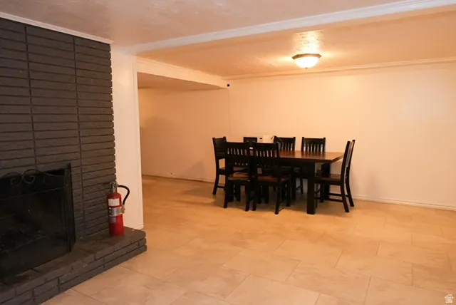 Recessed ceiling light, brick-faced fireplace, crown molding, and tiled flooring