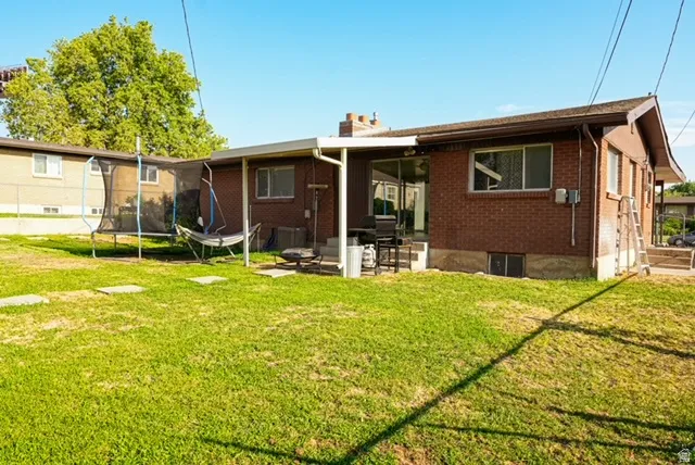 Brick exterior with a covered patio, expansive lawn, and sliding glass door access