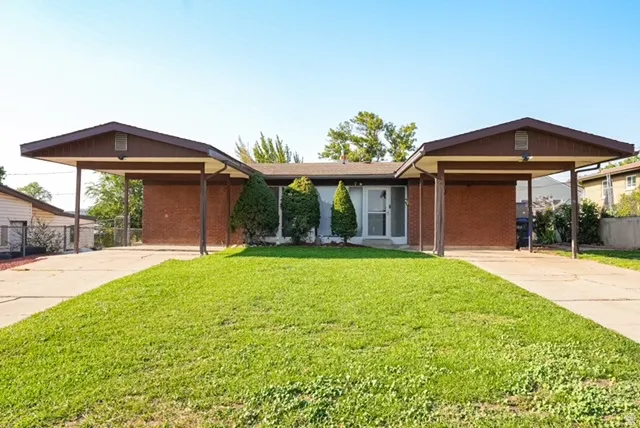 Mid-century modern exterior with brick facade, two carports, and a concrete driveway