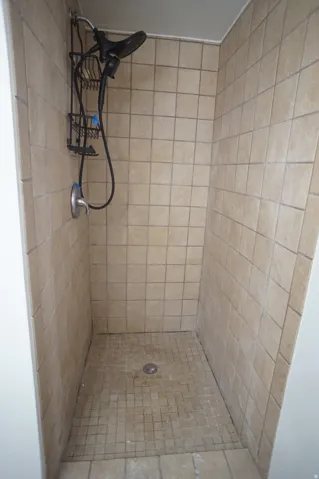 Tiled shower enclosure with a square grid floor and a wall-mounted showerhead