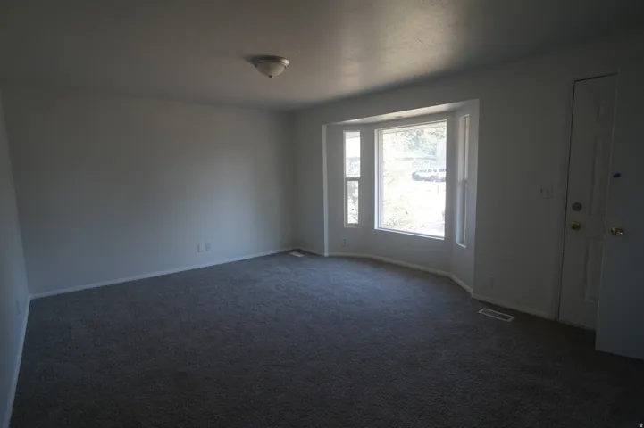 Carpeted interior space featuring a bay window, light-toned walls, and a ceiling-mounted light fixture